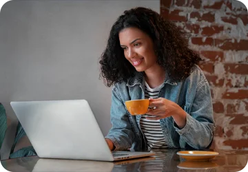 Mujer tomando un cafe e su computador